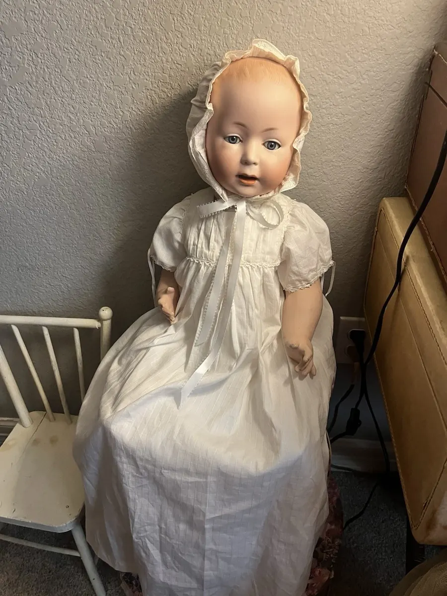 Full length, seated, the long white christening gown to the floor.