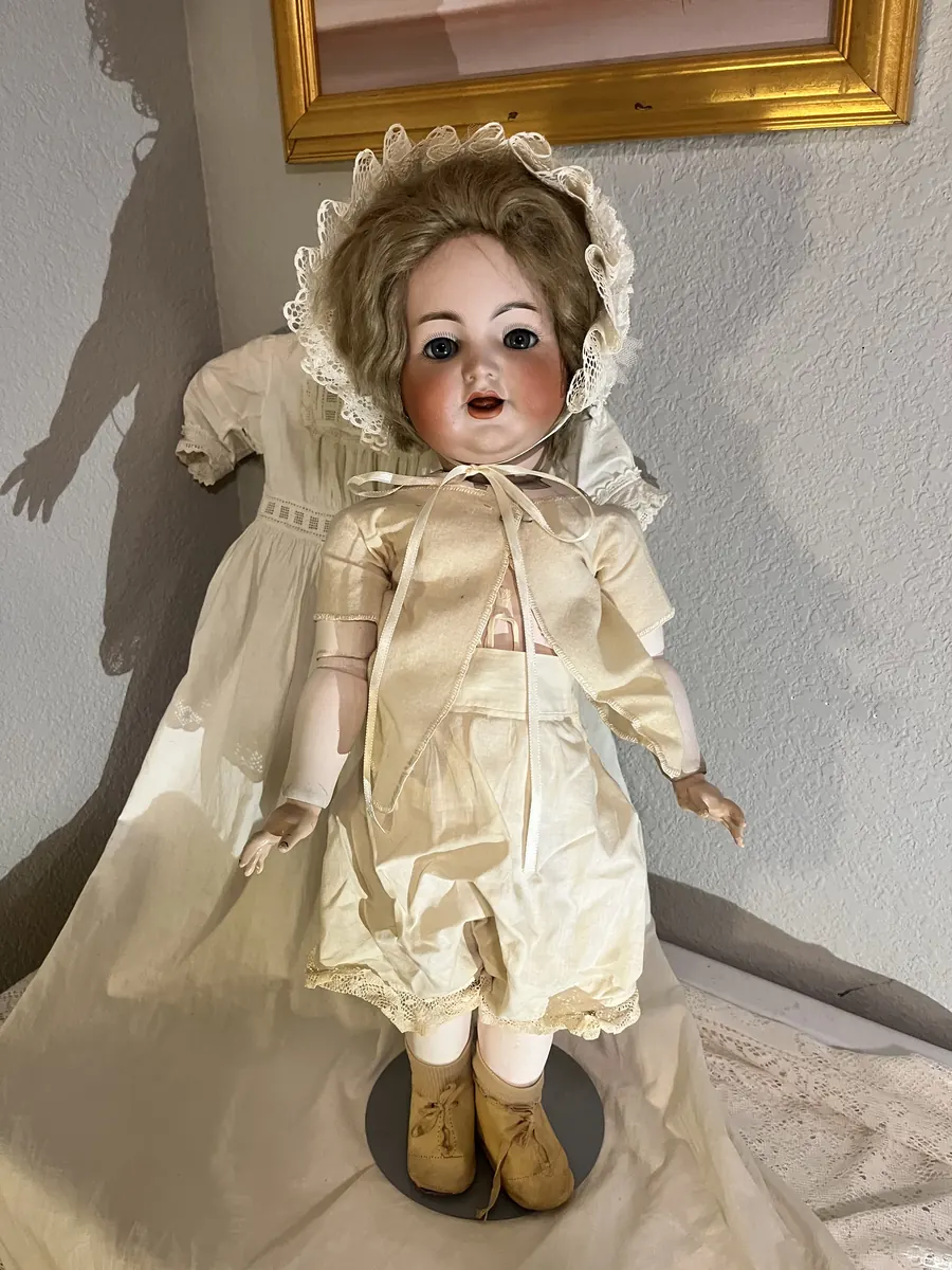 Simon and Halbig K*R 126 Toddler doll in a white dress on a stand, full view.